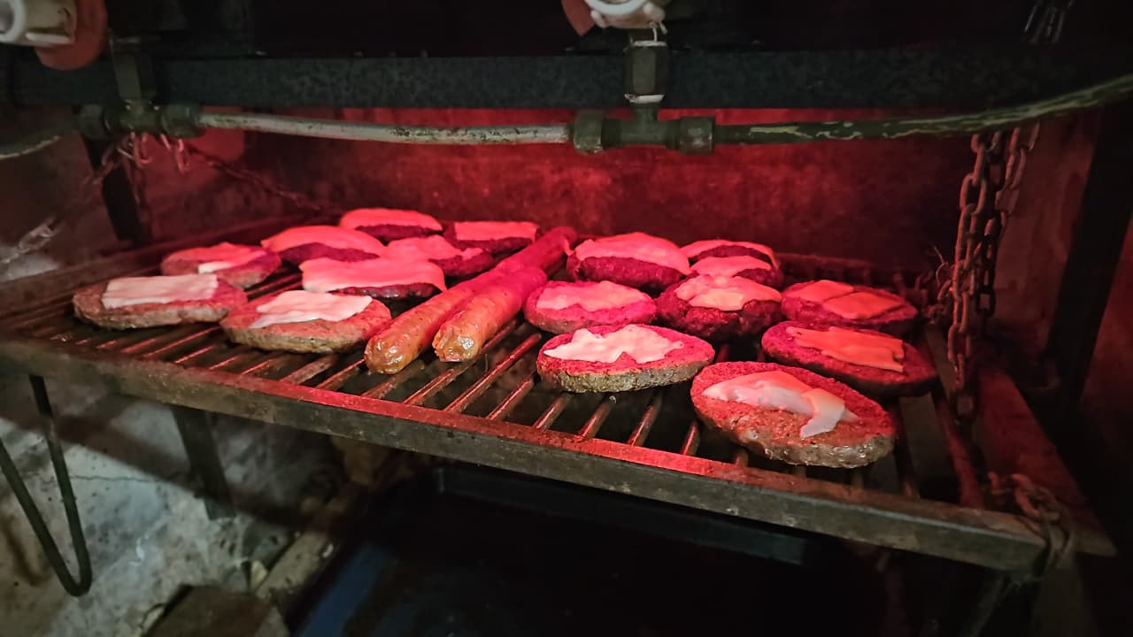 Hamburguesas y chorizos cocinándose a la parrilla
